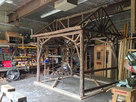 Rustic garden pavilion built using bark-on trees and branches titled the Martin Pavilion