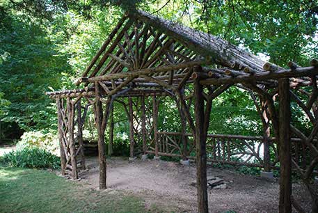 Rustic garden pavilion built using bark-on trees and branches titled the Martin Pavilion