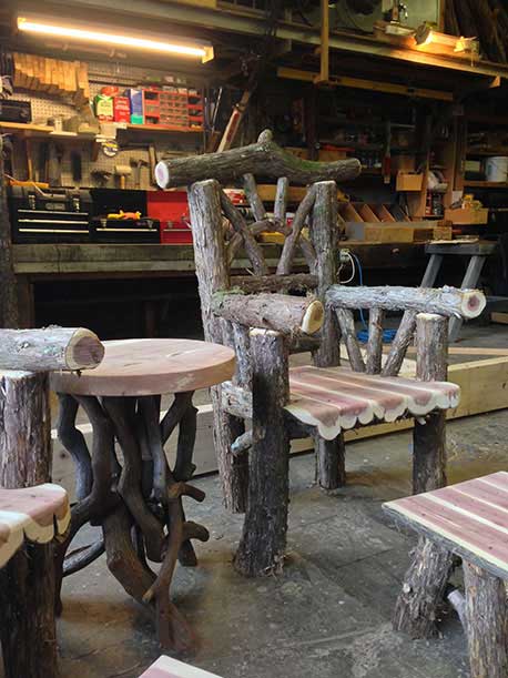 Outdoor rustic garden chairs built using bark-on trees and branches titled the Windham Chairs, Ottomans and Table