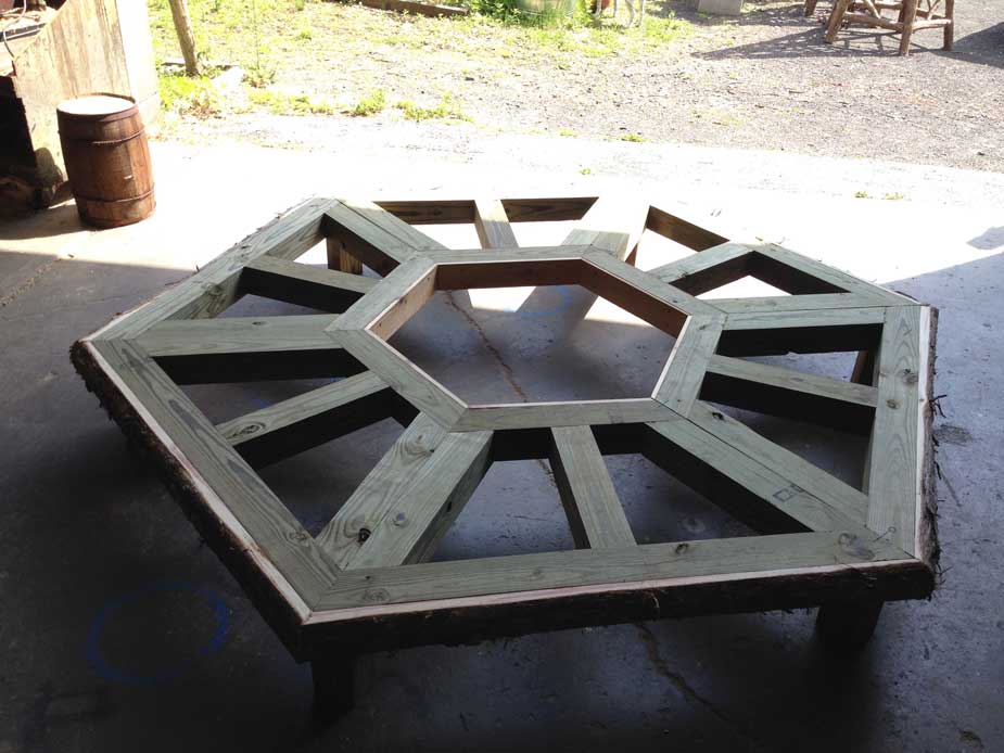 Natural wood bench built around a tree constructed using trees and branches titled the Alice Austen Tree Bench