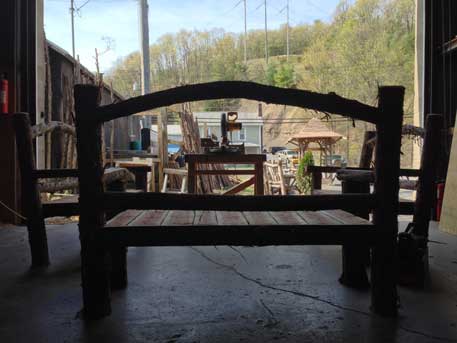 Outdoor rustic garden bench built using bark-on trees and branches titled the Maverick Bench