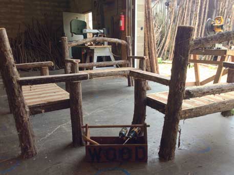 Outdoor park bench built in the rustic style using logs and branches titled the Maverick Bench