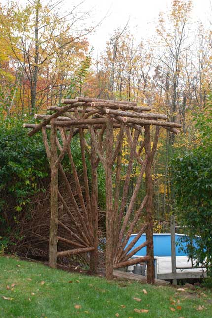 Natural wood rustic pergola built with trees and branches titled the Sunburst