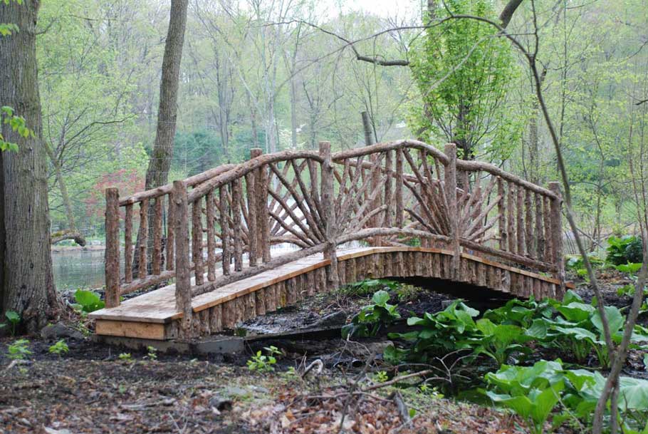 Natural wood bridge crossing a marsh built with trees and branches titled the Birdoff Bridge