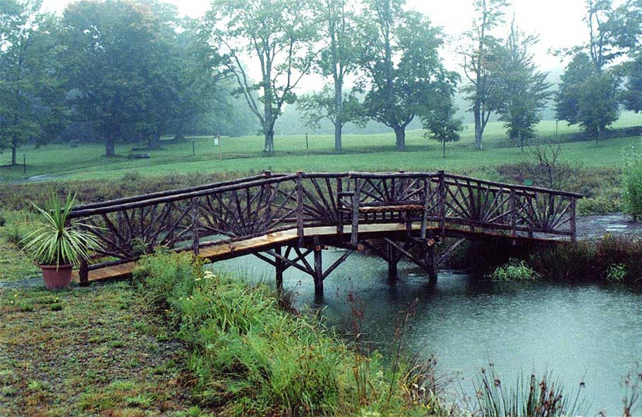 Bridge built in the rustic style over a stream using logs and branches at New Age Health Spa