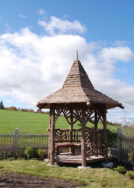 Rustic garden gazebo built using bark-on trees and branches titled the Midler Gazebo