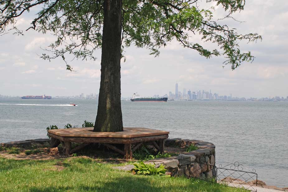 Outdoor rustic bench built around a tree using bark-on trees and branches at the Alice Austen House 