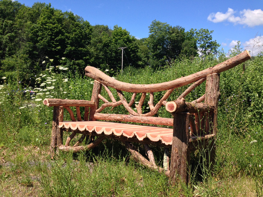 Exterior twig bench built from cedar logs titled the Falling Waters