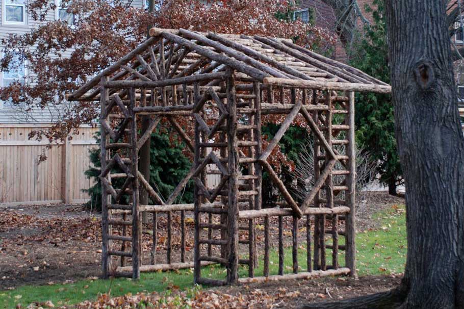 Natural wood covered bench built with trees and branches titled the Diamond Shelter