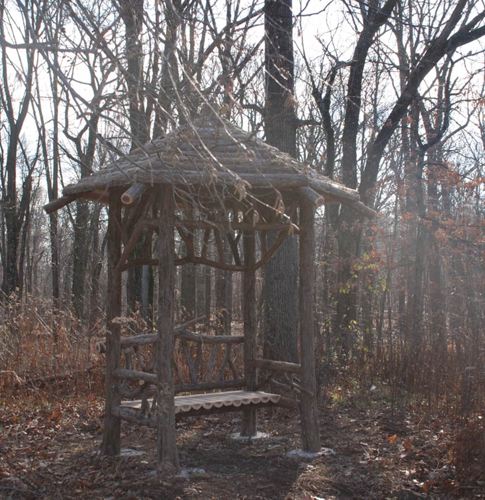 Outdoor rustic covered bench built using bark-on trees and branches titled the South Mountain Covered Bench