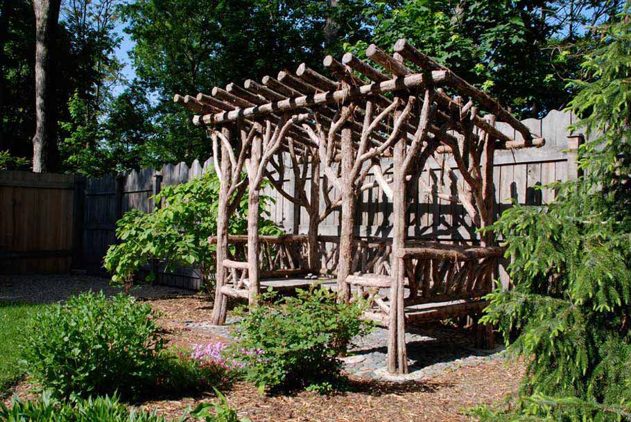 Natural wood covered bench built with trees and branches titled the Weedin Shelter