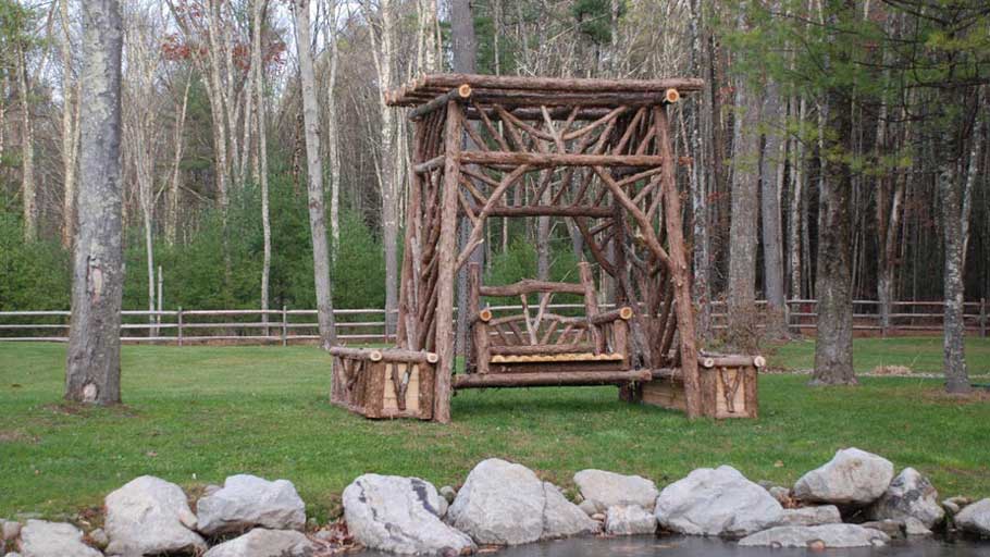 Natural wood bench swing and planters built with trees and branches titled the Belluck Bench Swing