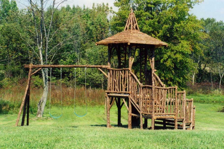Outdoor rustic playhouse and swing set built using bark-on trees and branches titled the Hudson Playhouse